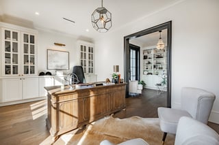 A very large home office with a wooden desk armchairs office chair built in shelving reading room