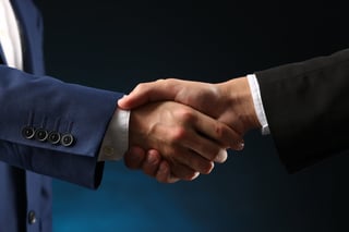 Business partners shaking hands on dark blue background